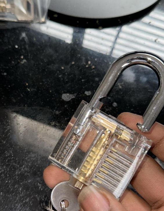 Close-up of a transparent padlock being held by a hand, showcasing its internal locking mechanism. This image highlights the intricate design and functionality of locks, emphasizing the craftsmanship essential for locksmith services.